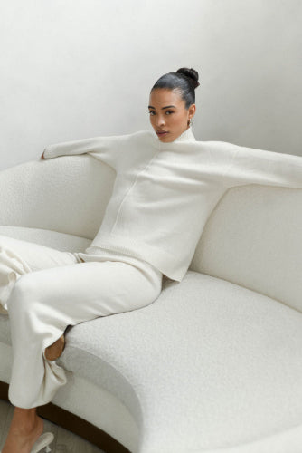 Person sitting on a white sofa with a plain background