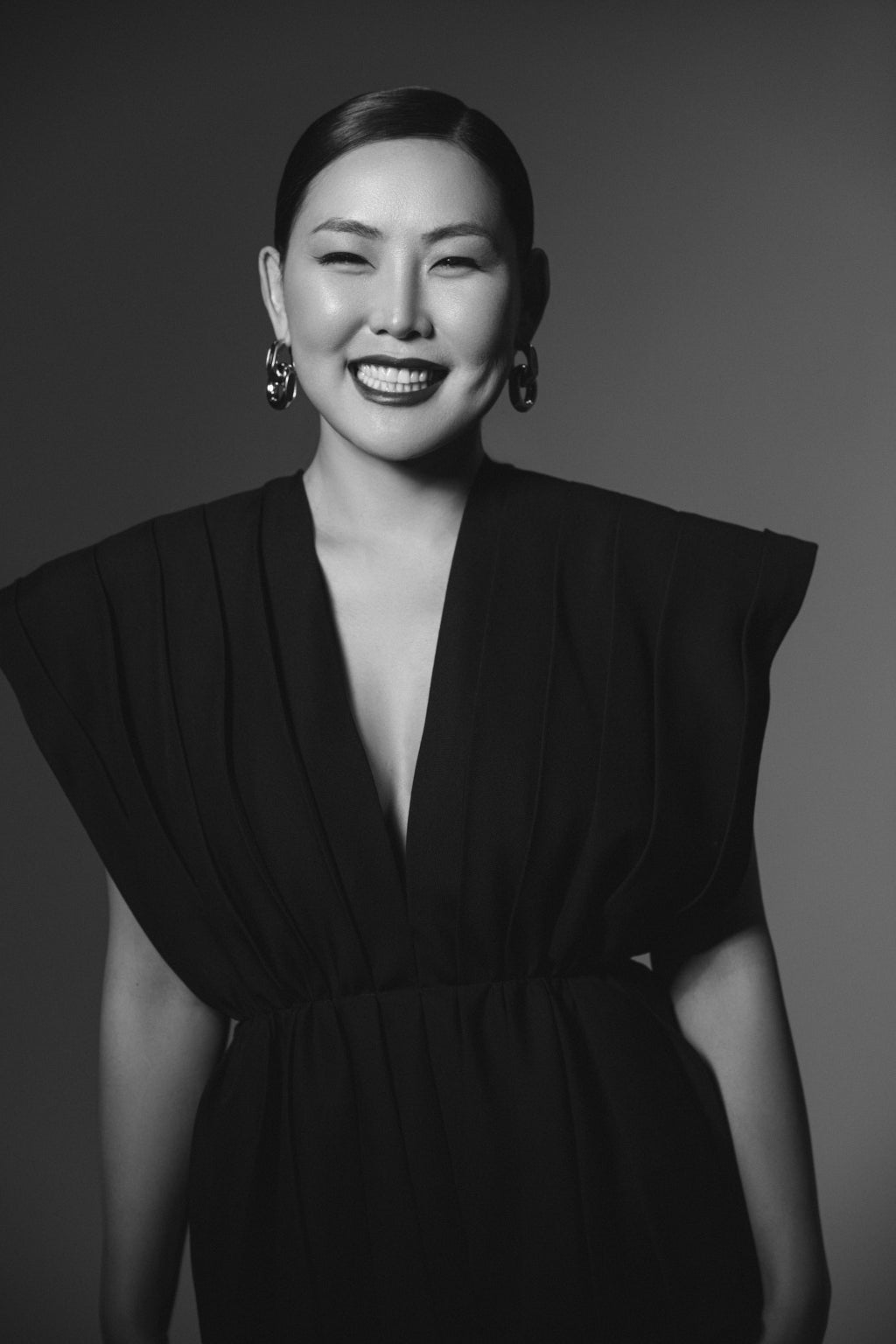 Black and white portrait of a woman wearing a black dress with a plunging neckline.