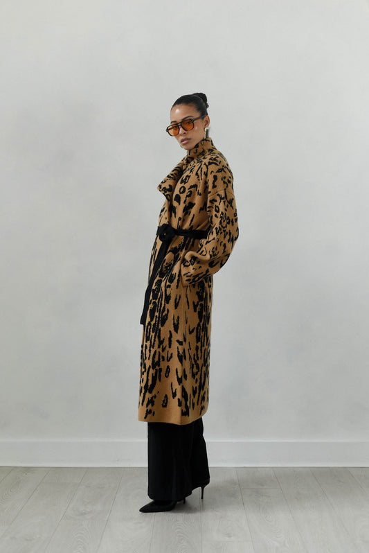Person wearing a long leopard print coat against a plain background