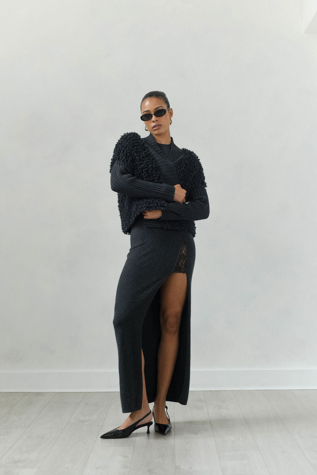 Woman wearing a black outfit with a high slit skirt against a white background