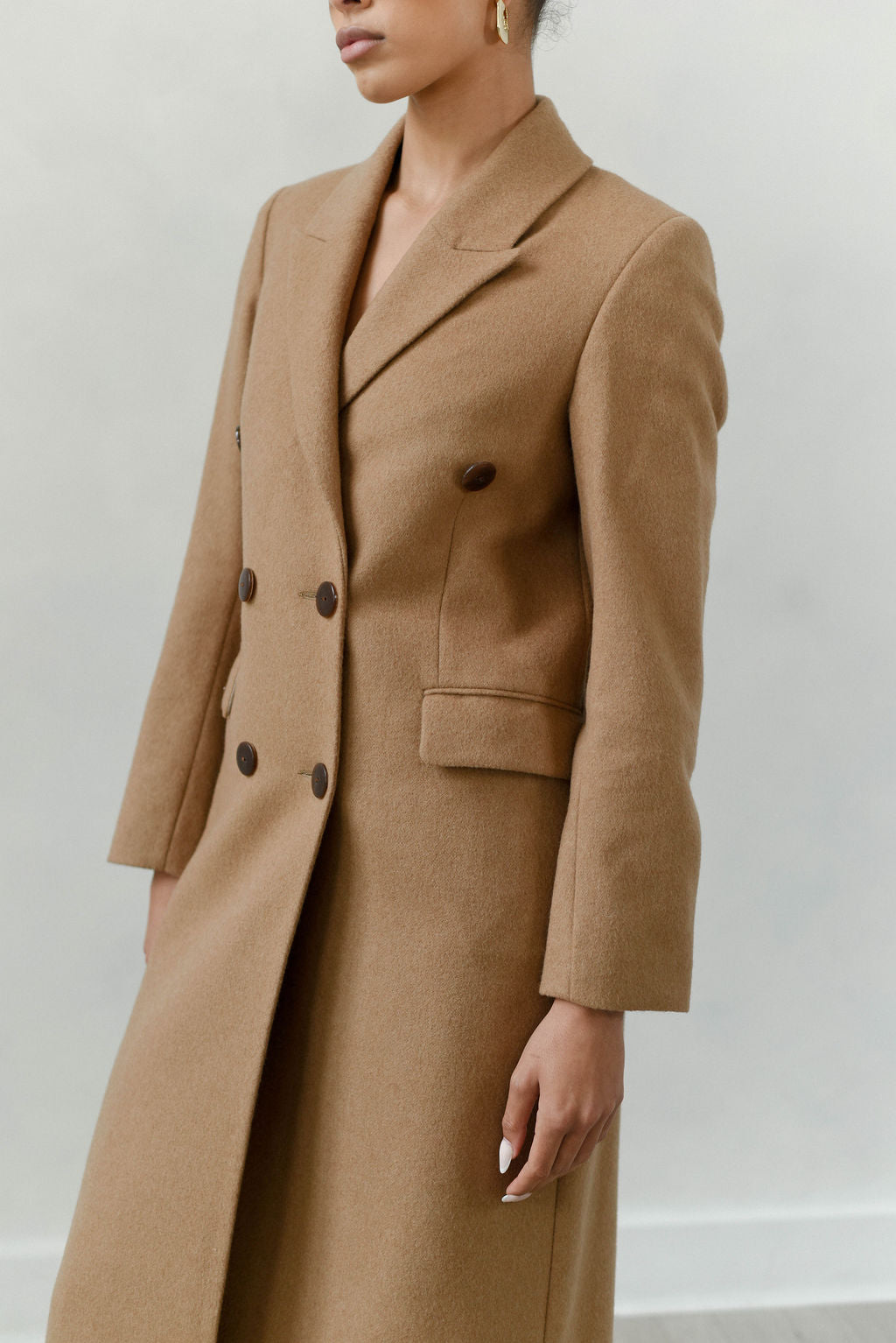 Person wearing a brown coat against a plain background