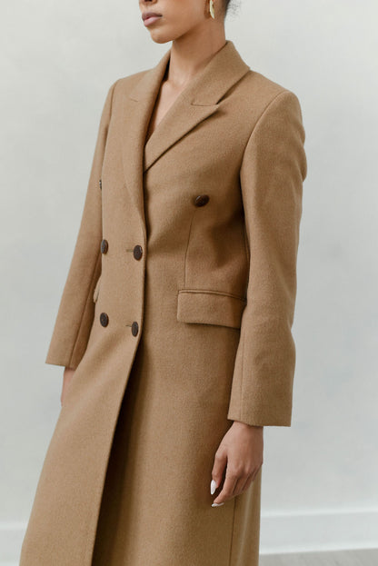 Person wearing a brown coat against a plain background