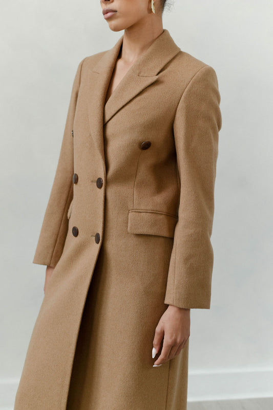 Person wearing a brown coat against a plain background