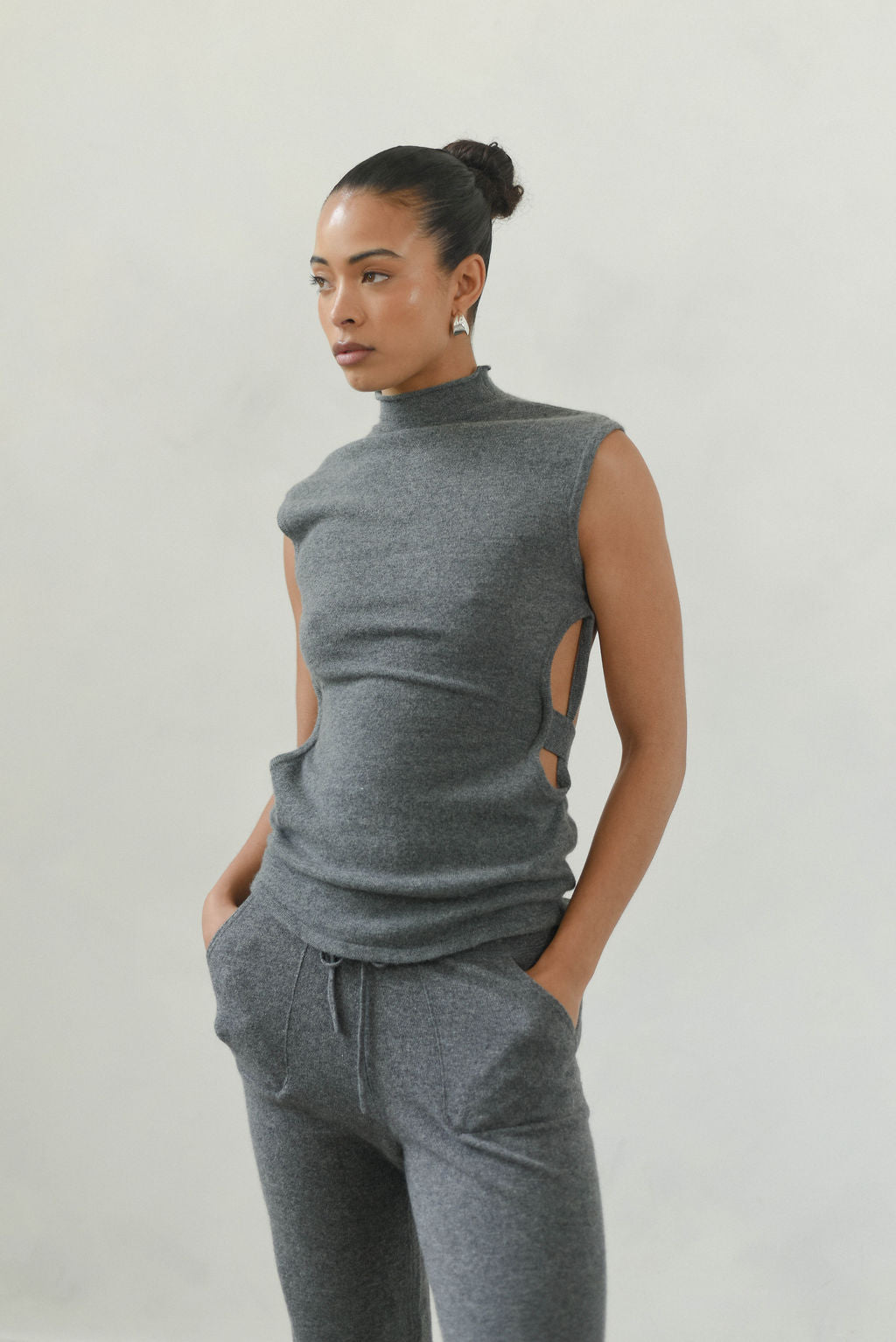Woman wearing a gray sleeveless top and pants against a plain background